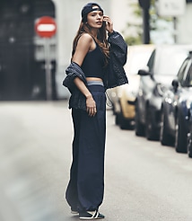 A young woman in a baseball cap and athletic wear stands on a street with parked cars in the background. carousel Product Image 1
