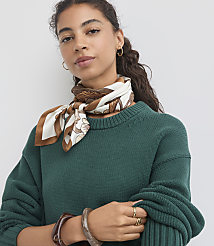 A woman with curly dark hair and a patterned silk scarf around her neck poses in front of a plain white background. carousel Product Image 1