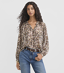 A woman in a floral blouse and jeans stands against a plain background. carousel Product Image 2