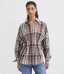 A woman in a brown plaid shirt and blue jeans stands against a plain white background. carousel Product Image 1
