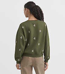 A woman wearing a green embroidered sweatshirt and brown pants stands against a plain white background. carousel Product Image 3