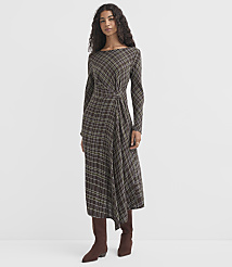 A woman in a plaid dress and boots stands against a plain, light gray background. carousel Product Image 1