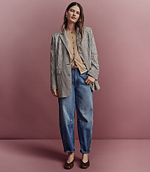 A woman in a checkered blazer, tan cardigan, and baggy jeans stands against a pink background. carousel Product Image 4