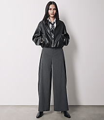 A woman in a black leather jacket and pinstripe pants stands against a plain white background. carousel Product Image 4