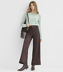 A woman in a light green sweater and brown wide-leg pants stands against a plain white background. carousel Product Image 1
