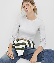 A woman in a grey long-sleeved shirt and jeans sits in front of a plain white background, with a striped sweater tied around her waist. carousel Product Image 1