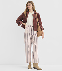 A woman in a maroon jacket and pink striped pants stands against a plain white background, holding a brown purse. carousel Product Image 1