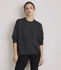 A woman in a dark grey sweater and black pants stands against a plain, light grey background. carousel Product Image 1
