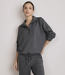 A woman in a dark grey quarter-zip sweatshirt and matching pants stands against a plain, light grey background. carousel Product Image 1