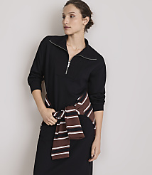 A woman in a black dress with a striped sweater tied around her waist stands against a plain gray background. carousel Product Image 2