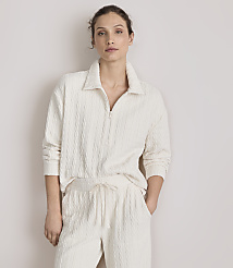A woman in a cream-colored cable-knit loungewear set stands against a plain, light-colored wall. carousel Product Image 2