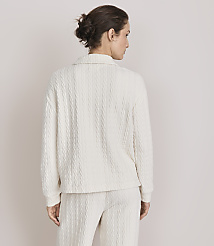 A woman in a cream cable-knit sweater and pants stands against a plain, light-colored background. carousel Product Image 3