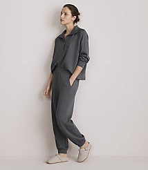 A woman in a grey loungewear set stands against a plain, light-colored wall. carousel Product Image 1
