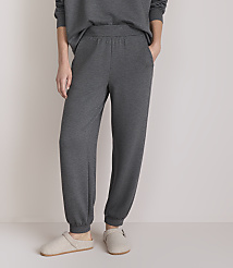 A person stands in comfortable grey loungewear and slippers against a plain, light-colored background. carousel Product Image 2