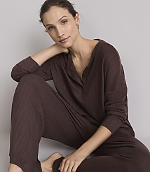A woman in brown loungewear rests her head on her hand against a plain gray background. carousel Product Image 1