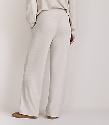 A person wearing light-colored, wide-leg lounge pants and slippers stands against a plain, light-colored background. carousel Product Image 3