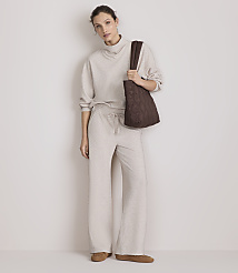 A woman in a beige loungewear set and brown tote bag stands against a plain, light-colored wall. carousel Product Image 1