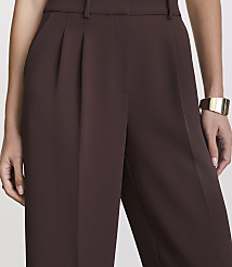 A close-up shot of a person wearing brown pleated pants and a gold bracelet against a plain background. carousel Product Image 4