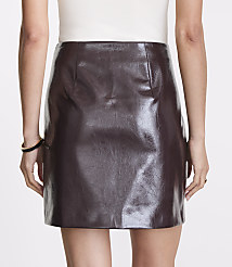 A woman in a white top and a dark brown faux leather mini skirt stands against a plain background. carousel Product Image 3
