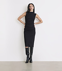 A woman in a black dress and boots stands against a plain white background. carousel Product Image 1