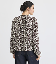 A woman in a floral blouse and dark jeans stands against a plain white background. carousel Product Image 3