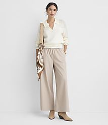 A woman in a cream collared sweater and beige pinstripe wide-leg pants stands against a plain white background, accessorized with a patterned scarf and a crossbody bag. carousel Product Image 1