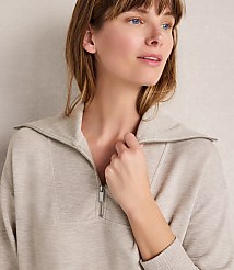 A woman in a beige quarter-zip sweatshirt looks off to the side against a neutral, textured background. carousel Product Image 3