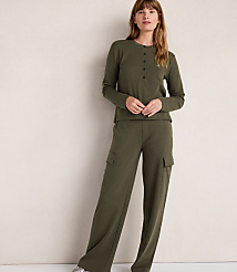 A woman in a green henley and cargo pants stands against a plain, light-colored wall. carousel Product Image 1