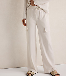A person wearing cream-colored wide-leg cargo pants and sandals stands against a textured cream background. carousel Product Image 2