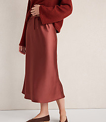 A person models a rust-colored satin midi skirt and a rust-colored sweater, standing against a plain white background. carousel Product Image 2