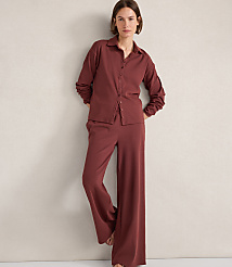 A woman in a maroon pajama set stands against a textured off-white wall. carousel Product Image 2
