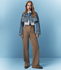 A young woman in a denim jacket and wide-leg pants stands against a solid blue background. carousel Product Image 5