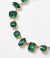 A gold necklace with various emerald-cut and round green gemstones is displayed against a plain white background. carousel Product Image 2