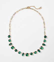 A gold chain necklace with various green gemstones is displayed against a plain white background. carousel Product Image 1