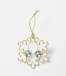 A pair of light blue crystal earrings hang from a gold string attached to a white snowflake ornament with gold trim, set against a plain white background. carousel Product Image 1