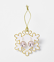 A pair of pink crystal earrings hangs from a gold string attached to a white snowflake ornament with gold trim, set against a plain white background. carousel Product Image 1