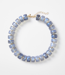 A necklace of blue, translucent, barrel-shaped beads with gold accents is displayed against a plain white background. carousel Product Image 1