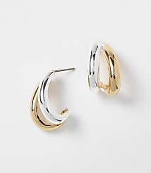 Two intertwined hoop earrings, one silver and one gold, rest on a plain white background. carousel Product Image 1