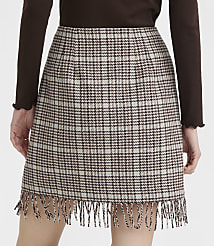 A brown and white plaid mini skirt with fringe detail is worn by a person against a plain background. carousel Product Image 4