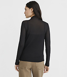 A woman in a black sheer turtleneck and brown pants stands against a plain white background. carousel Product Image 3
