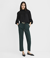 A woman in a black blouse and green pants stands against a plain white background. carousel Product Image 1