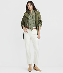 A woman in a green jacket, patterned blouse, and white pants stands against a plain white background. carousel Product Image 1