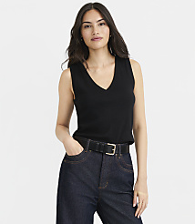 A woman in a black V-neck top and dark jeans stands against a plain white background. carousel Product Image 1
