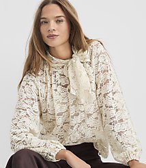 A woman with long brown hair wears a cream-colored lace blouse with a pussy-bow tie, against a plain white background. carousel Product Image 2