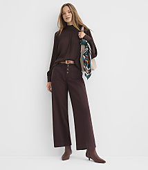 A woman in a brown mock-neck top and wide-leg pants stands against a plain white background, carrying a tote bag with a colorful scarf. carousel Product Image 2