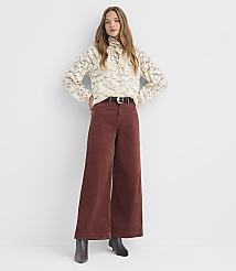 A woman in a cream lace blouse and rust-colored wide-leg corduroy pants stands against a plain white background. carousel Product Image 1
