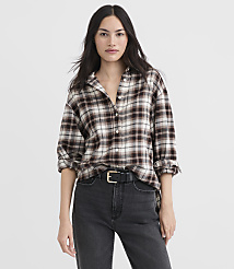 A woman in a brown plaid shirt and black jeans stands against a plain white background. carousel Product Image 1