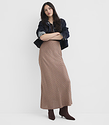 A woman in a patterned skirt and denim jacket stands with her arms crossed against a plain white background. carousel Product Image 1