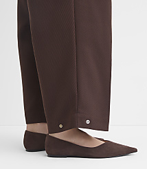 Brown suede flats peek out from beneath the hem of brown trousers adorned with silver buttons. carousel Product Image 3