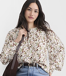 A woman in a floral blouse and jeans is shown with a brown bag over her shoulder against a plain background. carousel Product Image 1